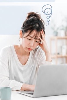 パソコンの前で悩む女性